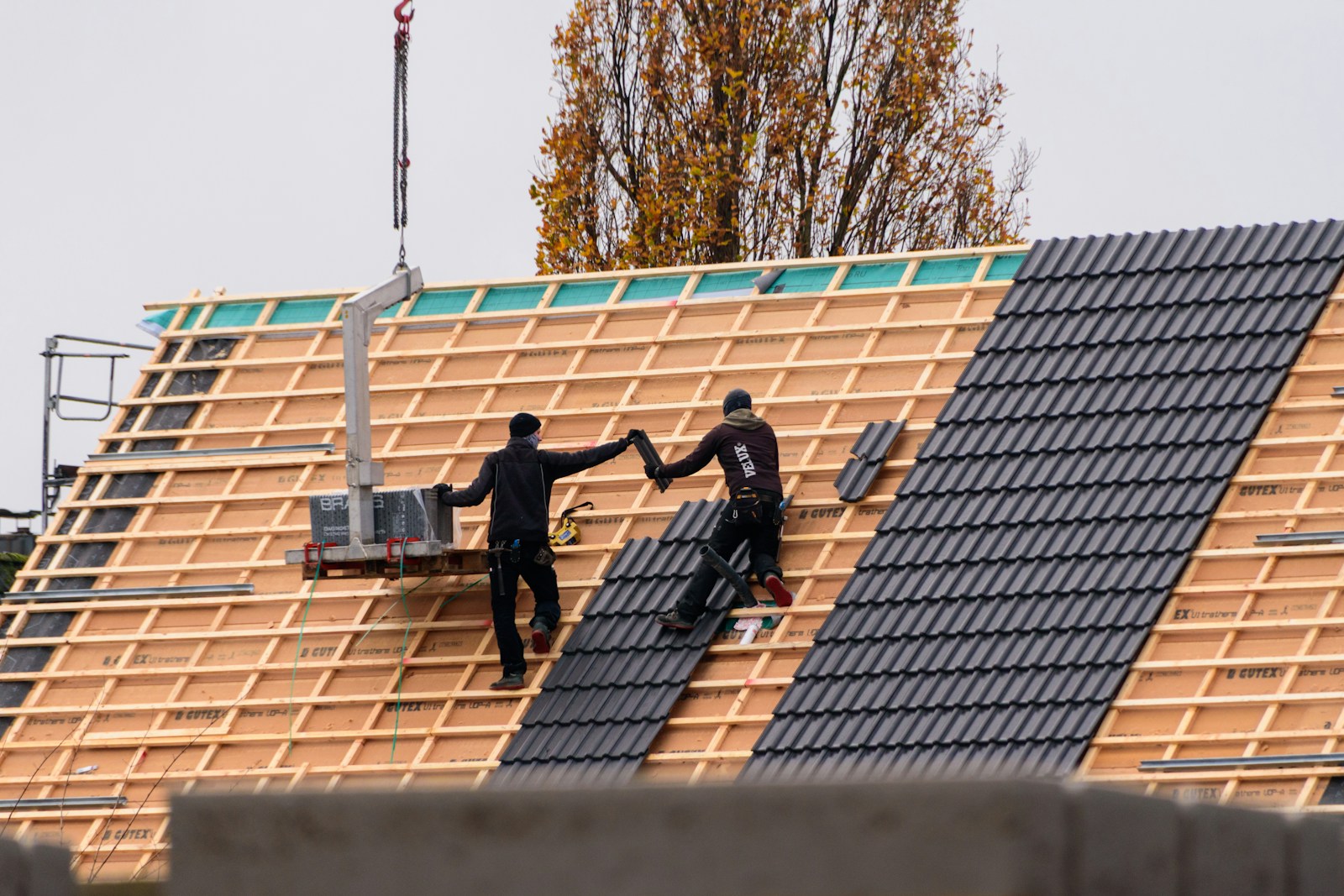 Workers installing roof tiles on a new building.